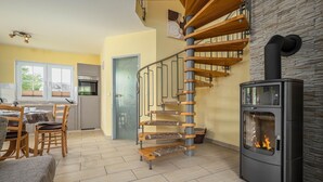 A modern kitchen with a built-in stove, a spiral staircase, and a dining area with wooden furniture. - Comfortable vacation home Am Deich House 16 with garden and terrace in Zingst - Am (Zingst)