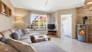 Een woonkamer met een bank, tv-meubel en een open haard.