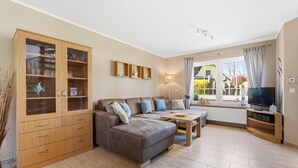 Een woonkamer met een bank, een tv-meubel en een houten kast.