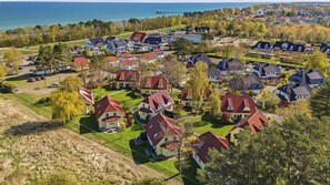 An aerial view of a residential area with houses, roads, and a body of water in the background. - Comfortable vacation home on the dyke with terrace, garden and fireplace in Zingst - Am (Zingst)