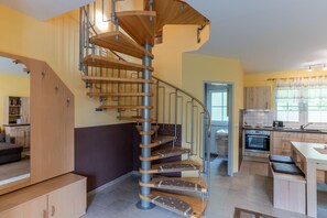 A modern kitchen with a spiral staircase, wooden cabinets, and a dining area. - Comfortable vacation home on the dyke with terrace, garden and fireplace in Zingst - Am (Zingst)