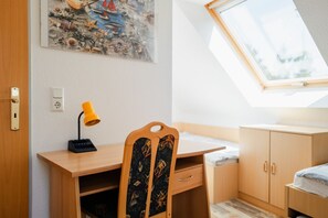 Ein Zimmer mit Schreibtisch, Stuhl und einem Oberlicht.