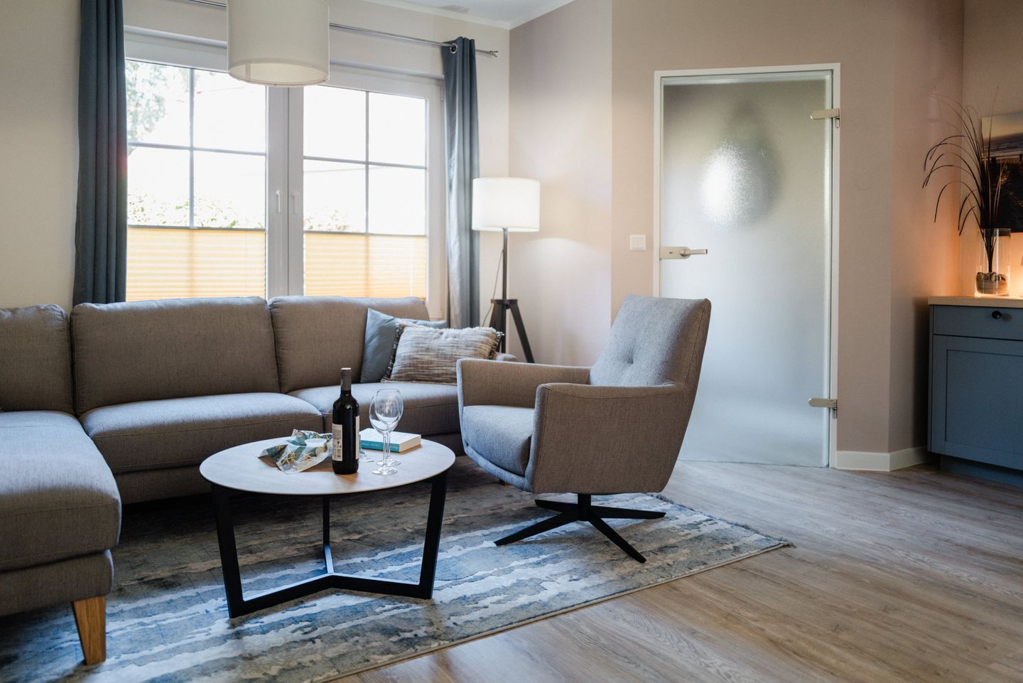 A modern living room with a sofa, armchair, coffee table, and a door.