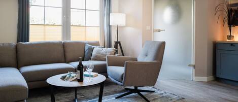 A modern living room with a sofa, armchair, coffee table, and a door.