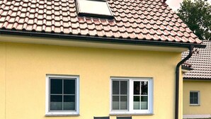 A yellow building with a tiled roof, two windows, and a patio with a table and chairs. - Family-friendly vacation home near the beach with garden and terrace in Zingst (Zingst)