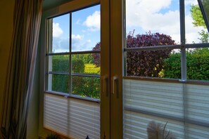 A room with a large window, a door, and a view of greenery outside. - Comfortable vacation home on the beach in Zingst with terrace and garden - Am Deich (Zingst)
