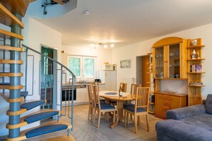 A modern kitchen with a dining area, a wooden staircase, and a built-in bookshelf. - Comfortable vacation home on the beach in Zingst with terrace and garden - Am Deich (Zingst)