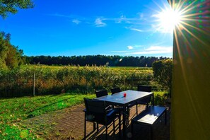 An outdoor patio with a table and chairs, surrounded by a grassy area and a fence. - Comfortable vacation home on the beach in Zingst with terrace and garden - Am Deich (Zingst)