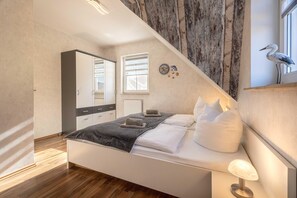 A modern bedroom with a bed, bedside table, and a wall-mounted lamp. - Semi-detached house close to the beach with 2 bedrooms in Zingst - Am Deich (Zingst)