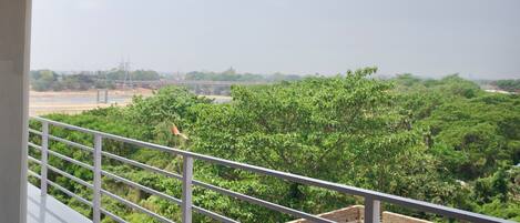 A balcony with a view of a construction site and greenery.