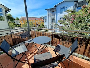 A balcony with a table and chairs, a railing, and a view of neighboring buildings. - Central but quiet, balcony, free swimming pool and sauna - Villa Elisenhof Elli 5 (Göhren)