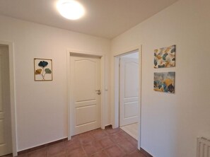 A hallway with two white doors, a ceiling light, and two wall-mounted artworks. - Central but quiet, balcony, free swimming pool and sauna - Villa Elisenhof Elli 5 (Göhren)