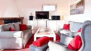 En stue med to grå sofaer, et hvidt sofabord, en pejs, et fjernsyn og et maleri på væggen.