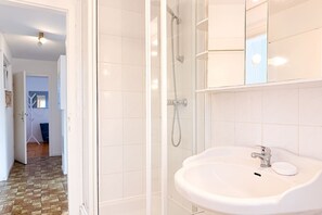 A bathroom with a glass-enclosed shower, a white sink with a soap dish, and a tiled floor. - (ULM1) Jürgens Lieblingsplatz Niendorf - Holiday home "Jürgens Lieblingsplatz (Timmendorfer Strand)