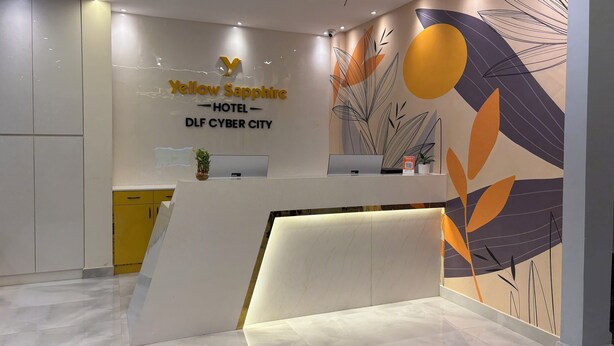 A hotel reception desk with a modern design, a digital screen, and a wall mural. - Yellow Sapphire Hotel DLF Cyber City (Hyderabad)