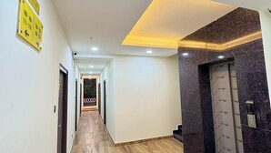 A hallway with wooden flooring, a ceiling light, and a sign indicating room numbers. - Yellow Sapphire Hotel DLF Cyber City (Hyderabad)