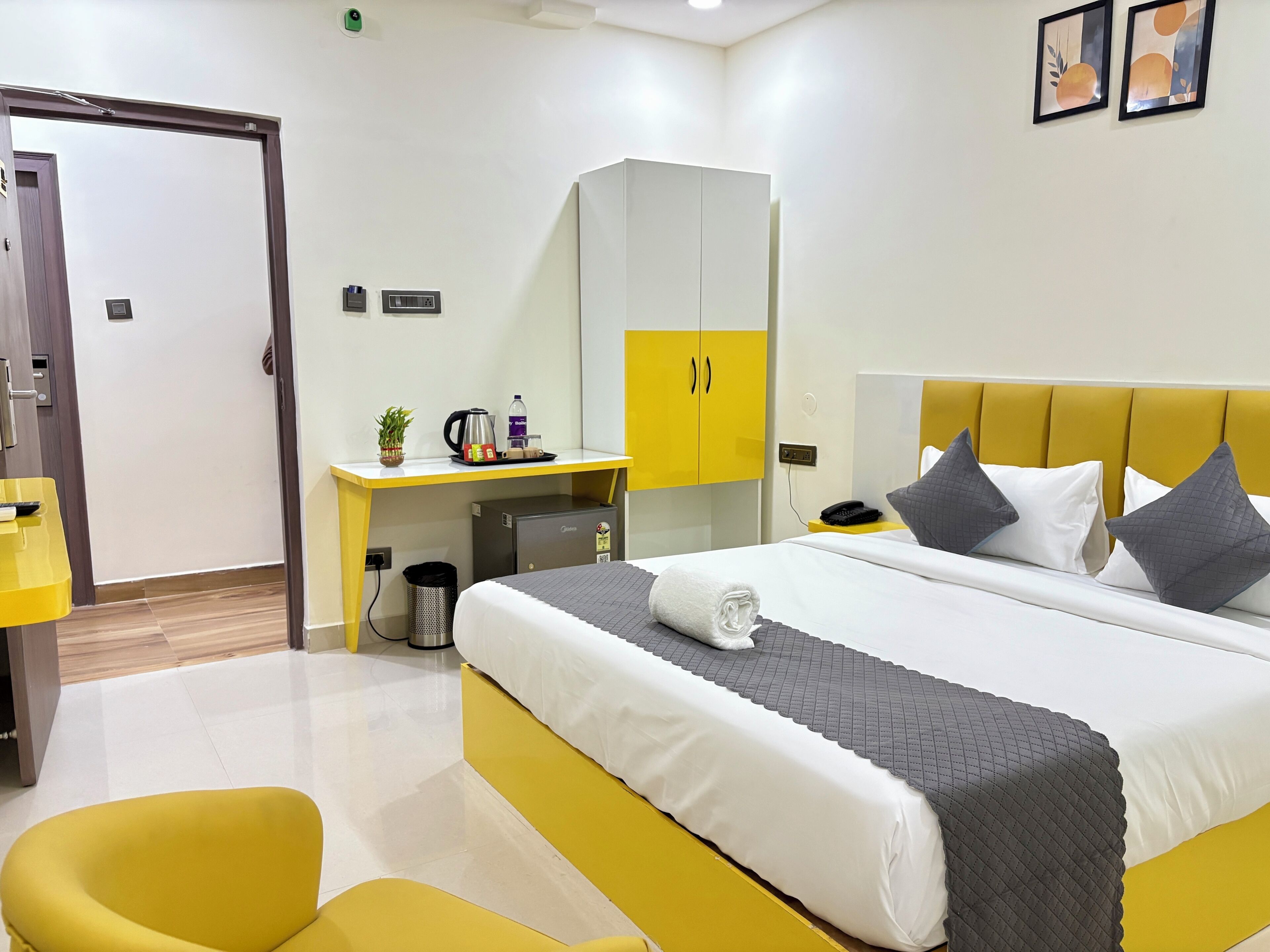Una habitación de hotel con cama, escritorio, silla, armario y cubo de basura.