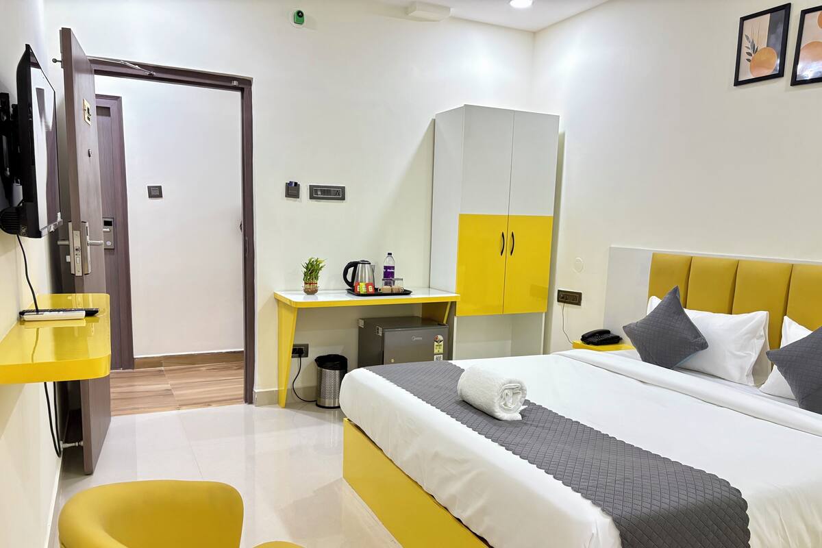 A hotel room with a bed, a desk, a chair, a wardrobe, and a television.