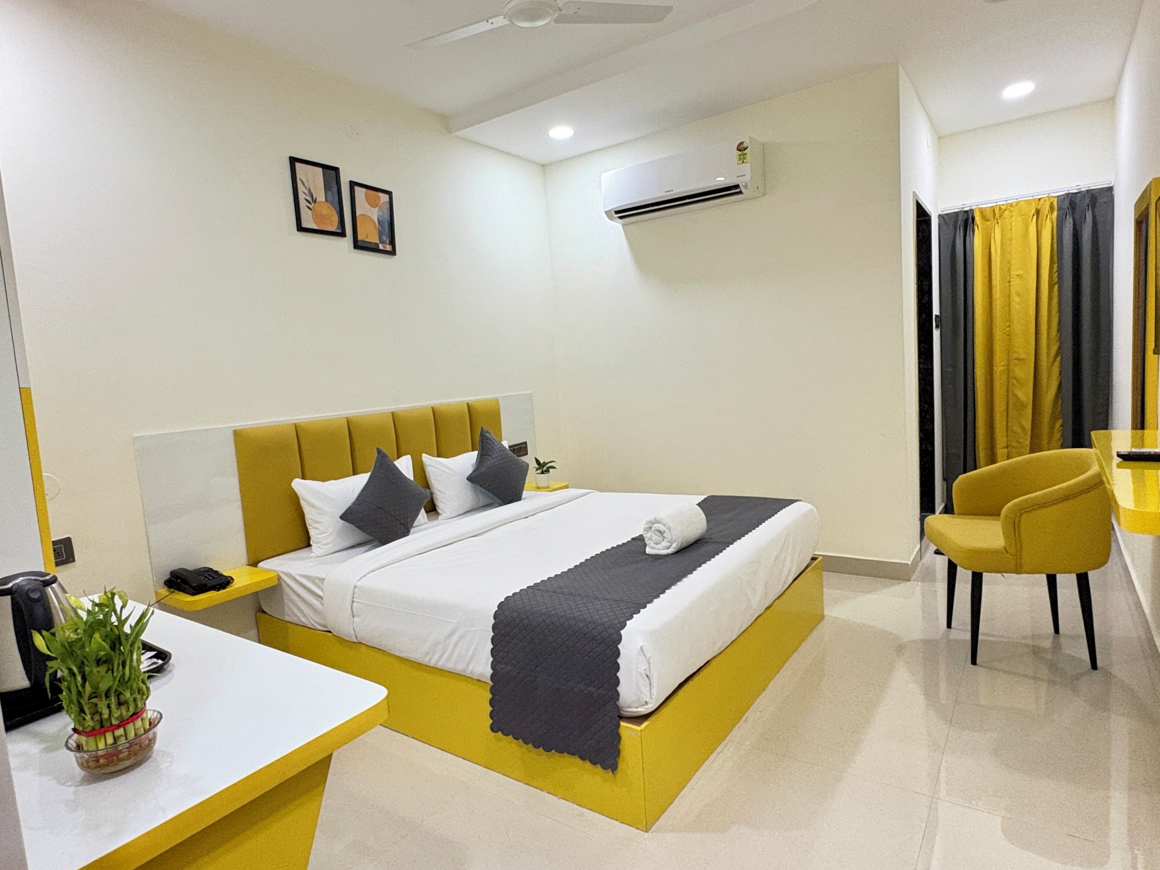 Ein modernes Hotelzimmer mit Bett, Nachttisch, Sessel und Klimaanlage.