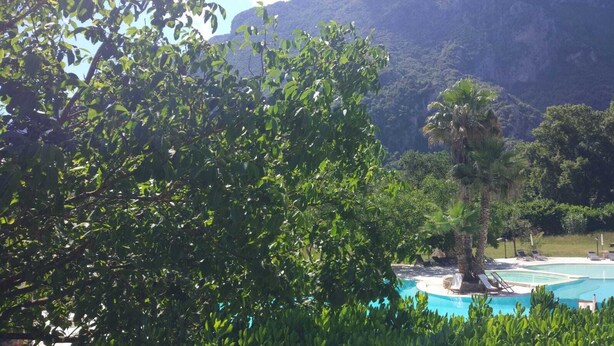 Piscina rodeada por vegetação exuberante e com montanhas ao fundo.