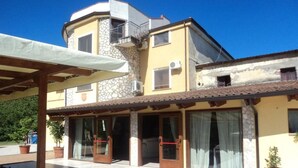 Um edifício de dois andares com fachada de pedra, grandes janelas e um terraço coberto.