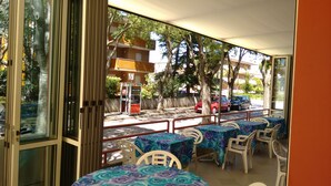 Un espace extérieur aménagé avec des tables et des chaises, donnant sur des voitures garées, et avec un bâtiment en arrière-plan.