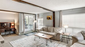 Ett vardagsrum med en soffa, ett soffbord och ett skrivbord med en lampa.