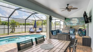 Ein überdachter Außenbereich mit Pool, Sitzgelegenheiten und Deckenventilator.