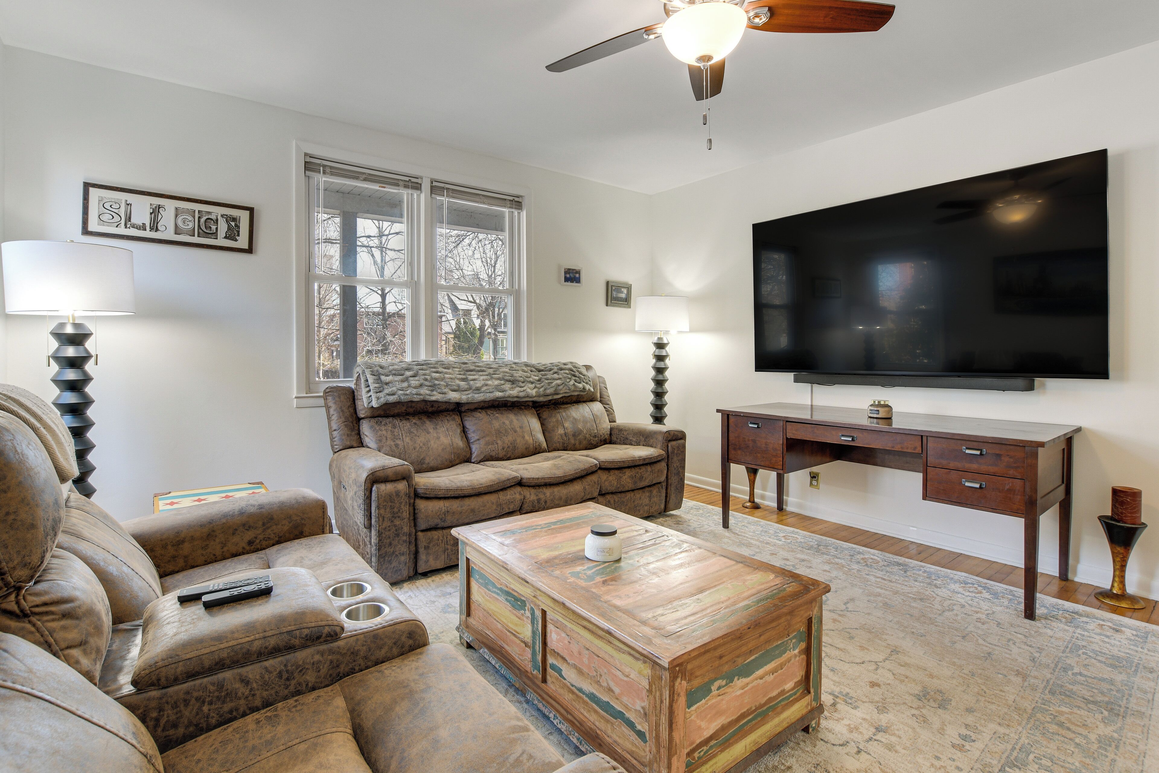 A living room with a sofa, a coffee table, a TV, and a ceiling fan.
