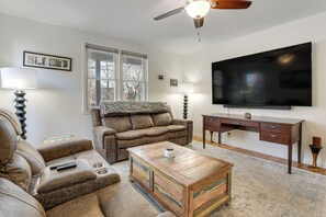 Una sala de estar con sofá, mesa de centro, televisor y escritorio.