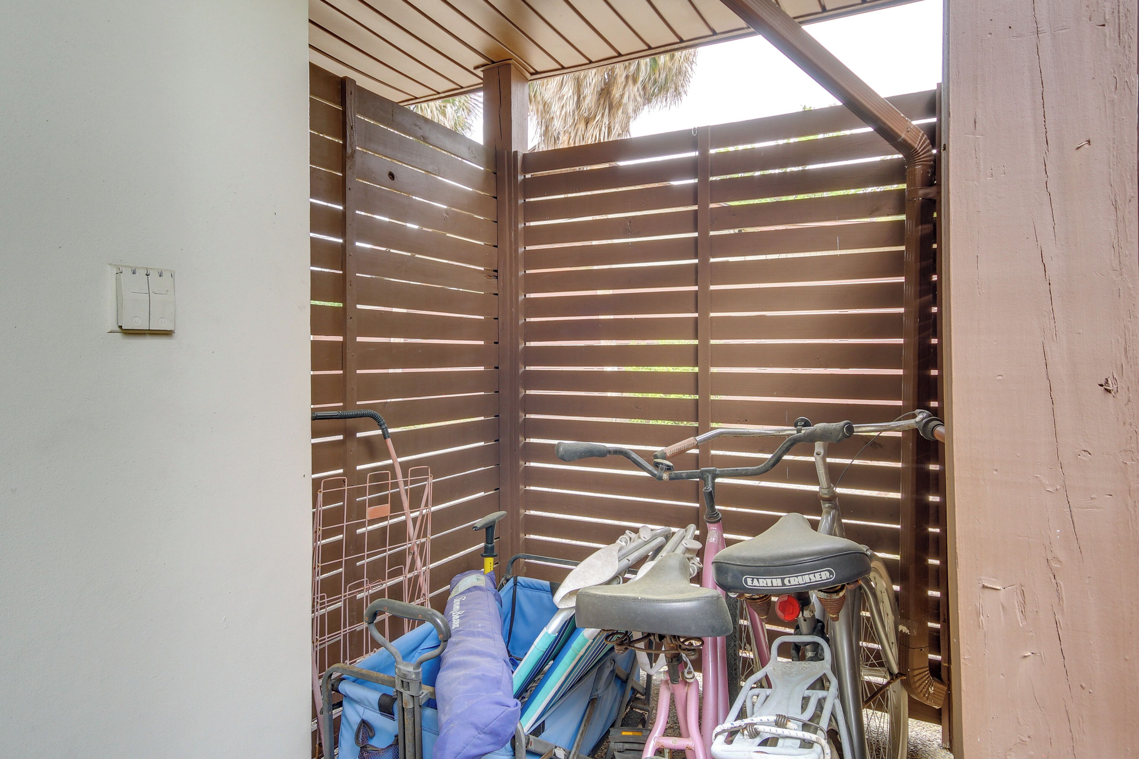 A covered outdoor area with a metal gate, bicycles, and a blue folding chair.