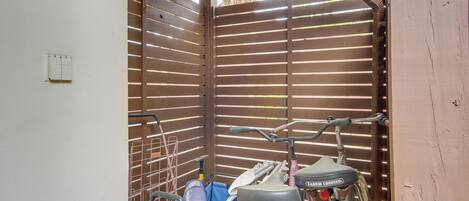A covered outdoor area with a metal gate, bicycles, and a blue folding chair.