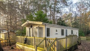 A mobile home with a porch, a small deck, and a fenced area. - Rawsons Retreat - -kelling Heath Holiday Park (Holt)