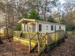 Ein Wohnmobil mit Veranda, einer kleinen Terrasse und einem umzäunten Bereich.