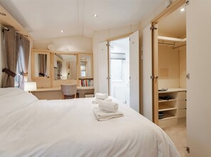 Ett hotellrum med en säng, ett skrivbord, en stol, en spegel och en garderob.