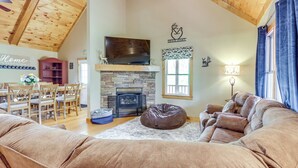 A cozy living room with a stone fireplace, a television mounted above it, and a comfortable seating area. - Sleeps 14 | Hot Tub, Game Room & 4 King Beds (Ellijay)