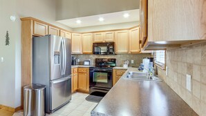 A modern kitchen with stainless steel appliances, wooden cabinets, and a granite countertop. - Sleeps 14 | Hot Tub, Game Room & 4 King Beds (Ellijay)