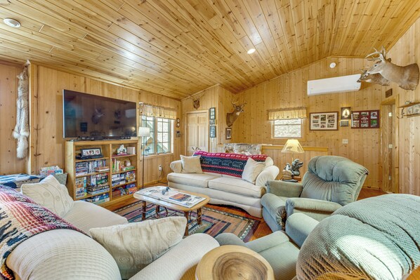 A wooden interior with a sofa, armchairs, a television, and a bookshelf. - On 4 Acres! Retreat w/ Lake Access in Maple City (Maple City)