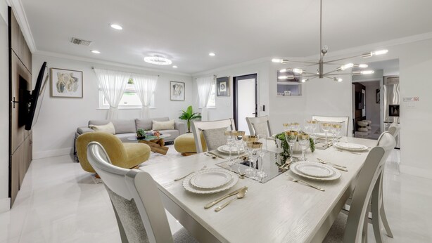 Een moderne eetruimte met een lange tafel voor zes personen, omringd door witte stoelen.