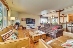 Ein Wohnzimmer mit Kamin, Ledersofas, einem Couchtisch und einem Fernseher.