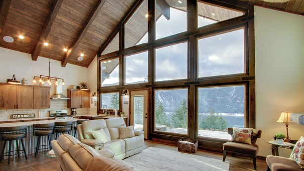 A spacious living area with a large window, a kitchen with wooden cabinets, and a cozy seating arrangement. - Game Room & Mtn Views: Large Cle Elum Lake House (Ronald)
