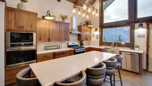A modern kitchen with wooden cabinets, a large island, and a view of the mountains. - Game Room & Mtn Views: Large Cle Elum Lake House (Ronald)