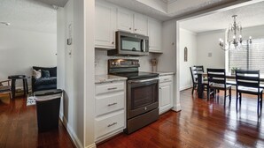 A kitchen with white cabinetry, a microwave, an oven, and a dining area with chairs and a table. - Lake Living & Game Room! Group Escape 3 Mi to HPU (High Point)