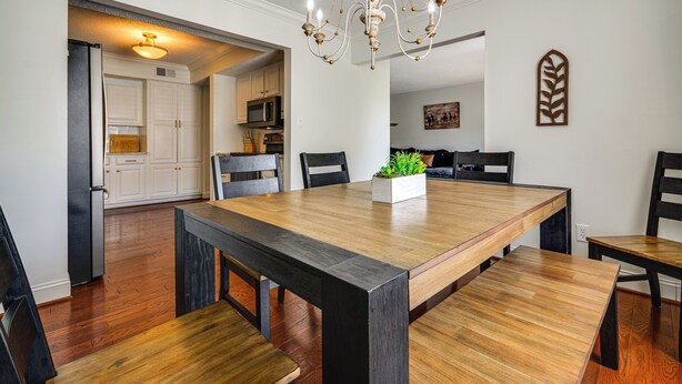 A dining area with a wooden table, chairs, a chandelier, and a kitchen in the background. - Lake Living & Game Room! Group Escape 3 Mi to HPU (High Point)
