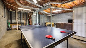 A ping pong table with two paddles, a brick wall, and a window with blinds. - Lake Living & Game Room! Group Escape 3 Mi to HPU (High Point)