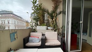 A balcony with a white table, two cushioned chairs, and potted plants. - 120sqm Downtown luxury flat big S-side balcony (Wien)