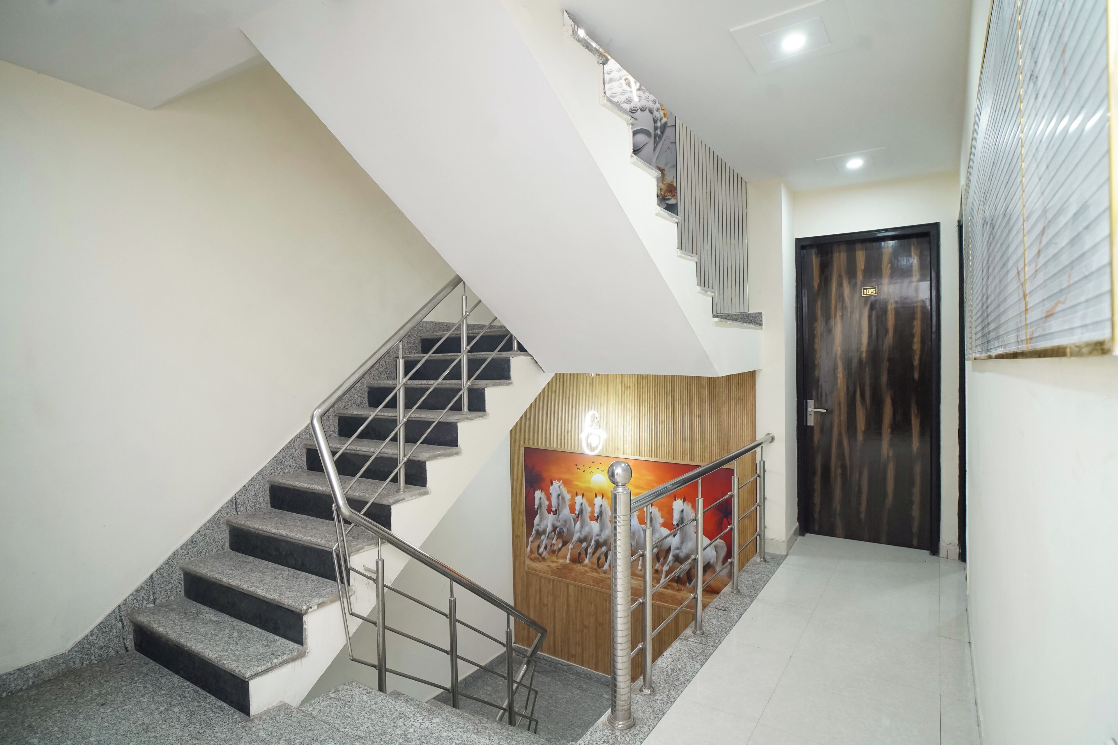 A staircase with metal railings, a wooden panel wall, and a door with a vertical striped pattern.