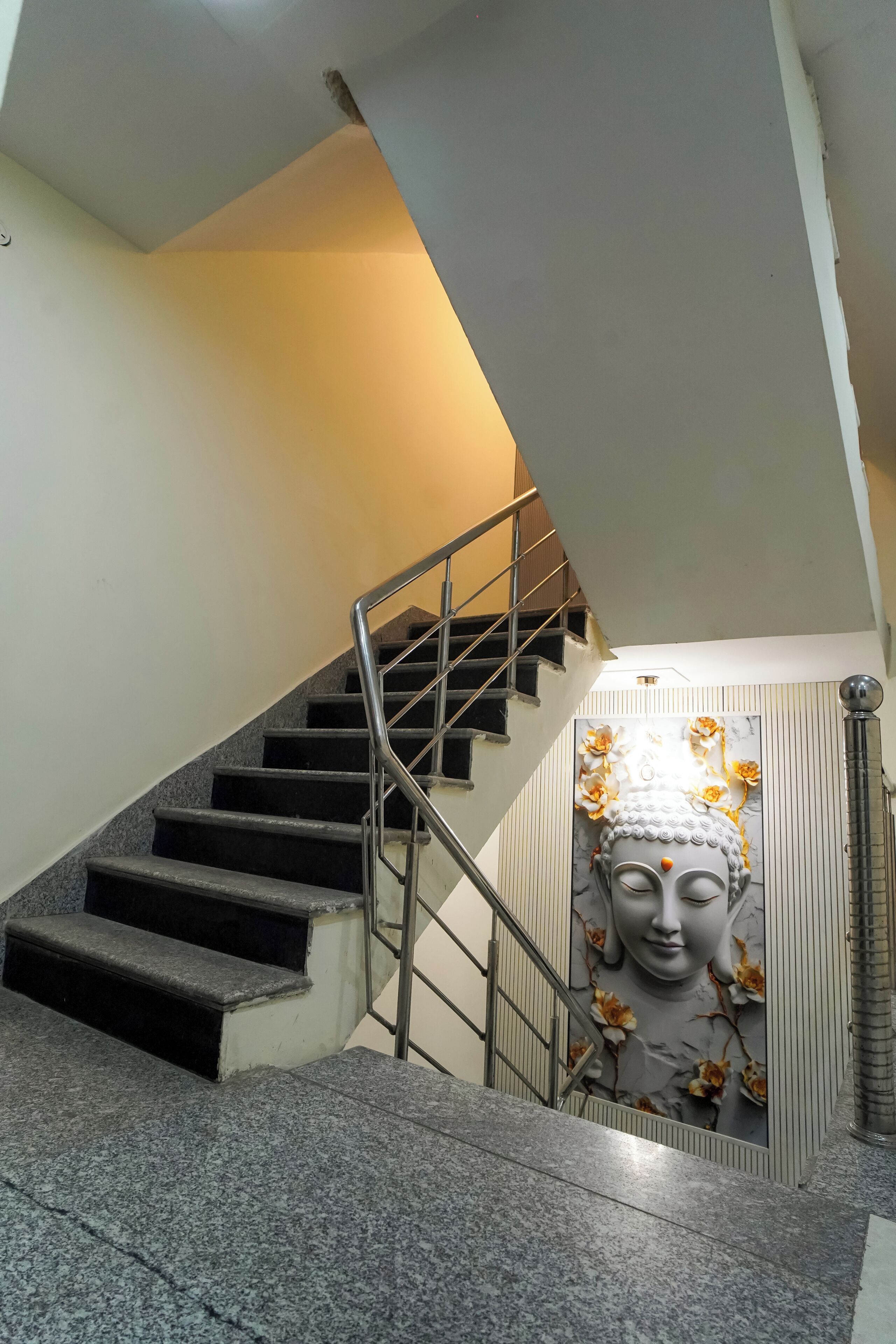 Eine Treppe mit Metallgeländer, Granitstufen und einer Wand mit einer Buddha-Statue.