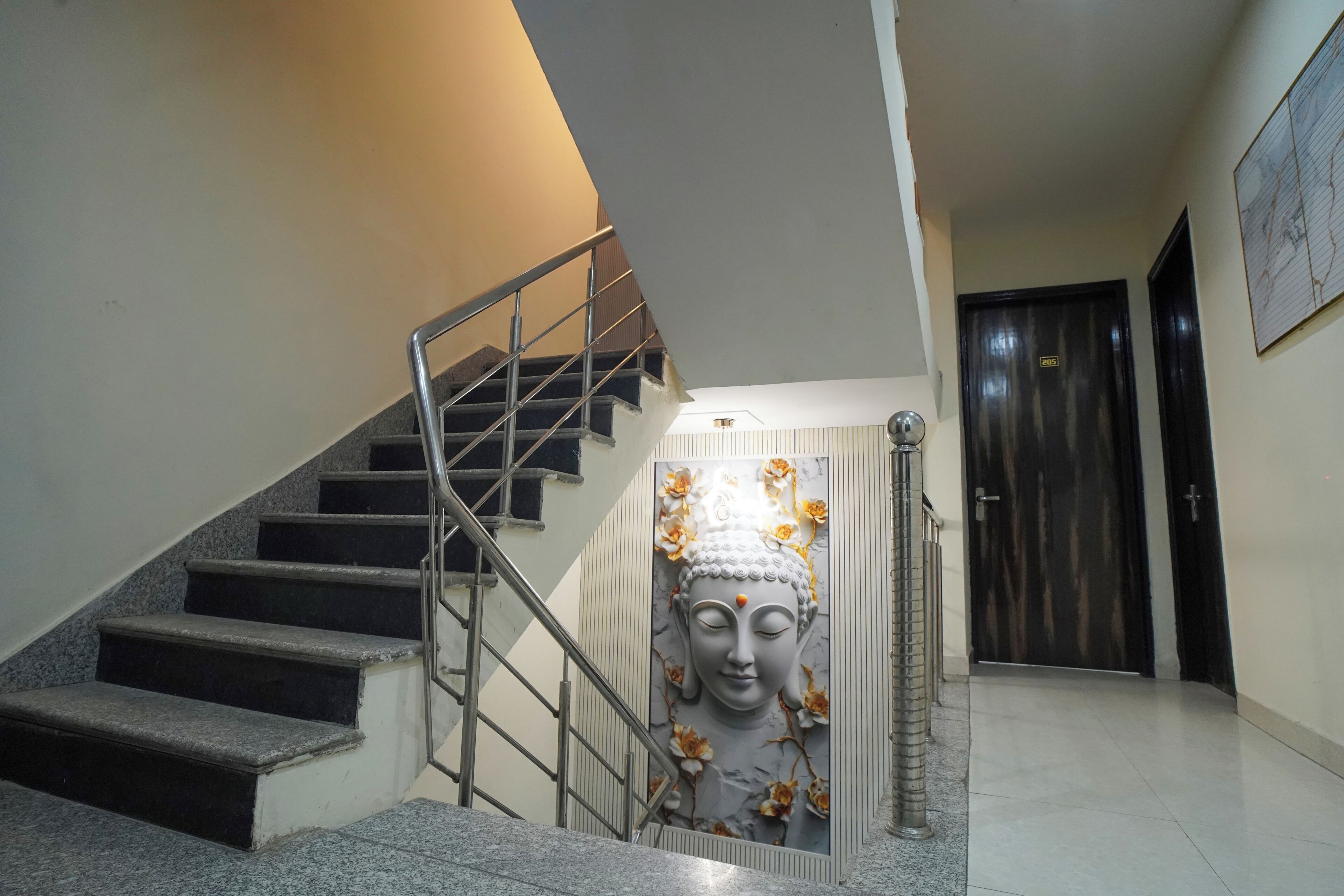 Eine Treppe mit Metallgeländer, eine an der Wand befestigte Buddha-Statue und eine Tür mit einem Schild.