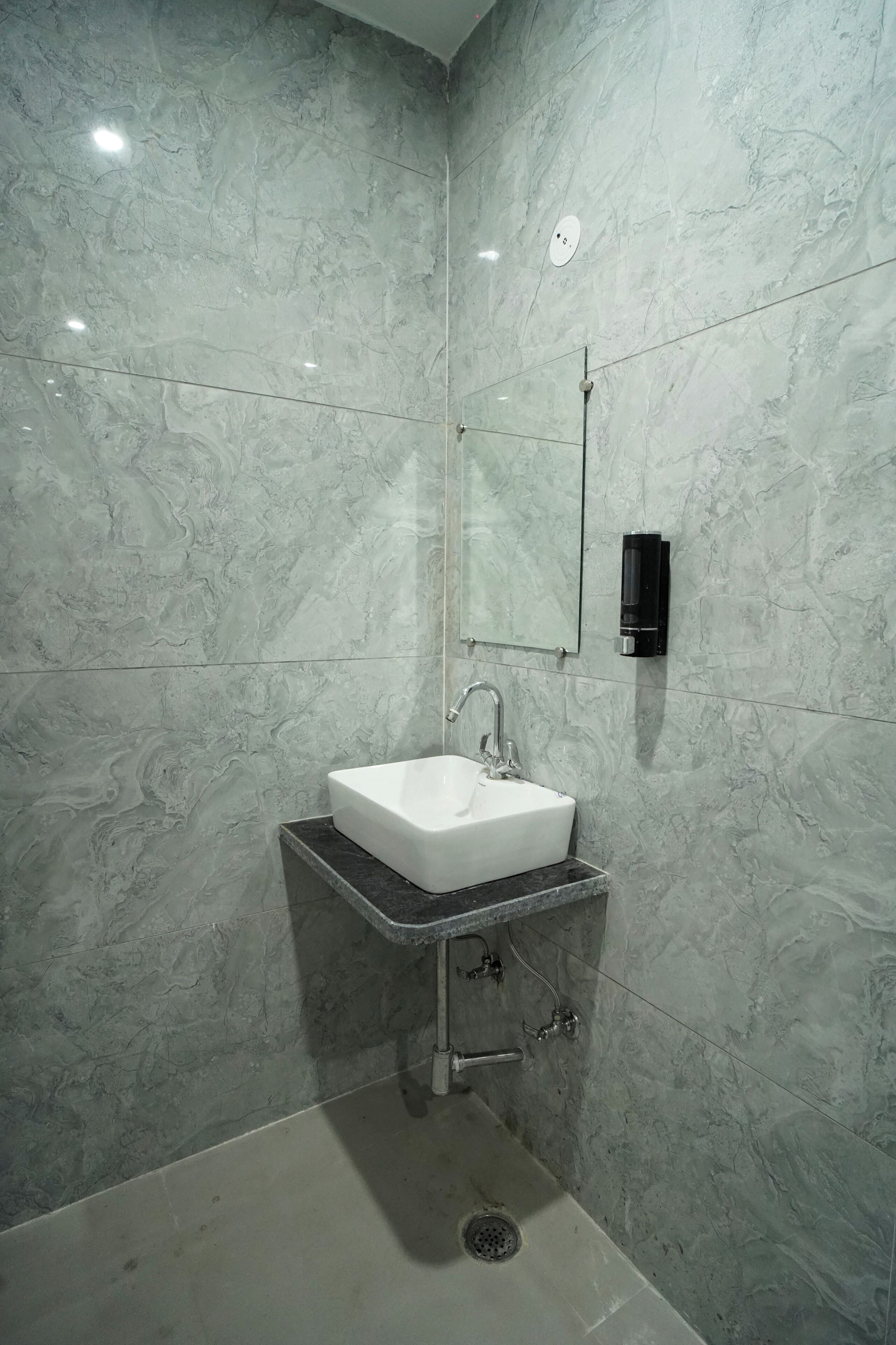 Un baño con lavamanos blanco, un espejo y un cabezal de ducha de mano.